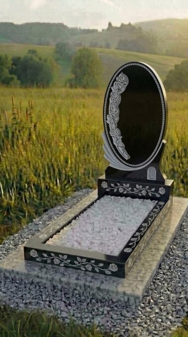 Овальный резной памятник из карельского гранита габбро-диабаза с цветочной композицией и декоративной рамкой